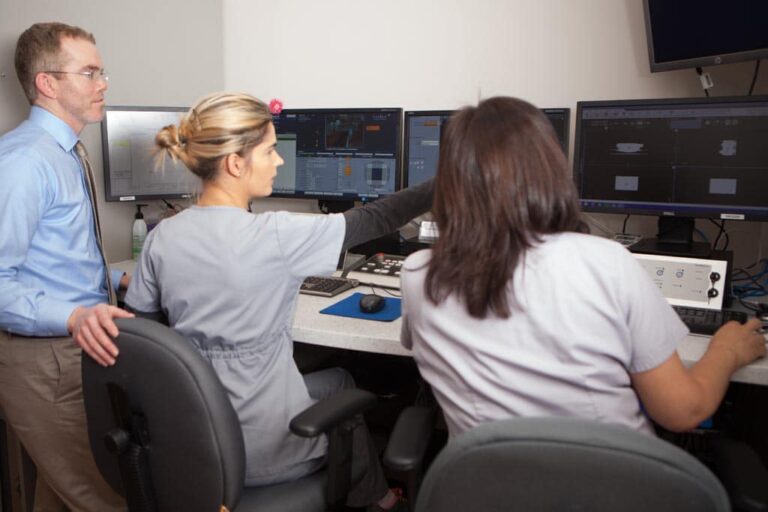 Radiation therapists and Dr. Brabham review patient results on a computer screen.